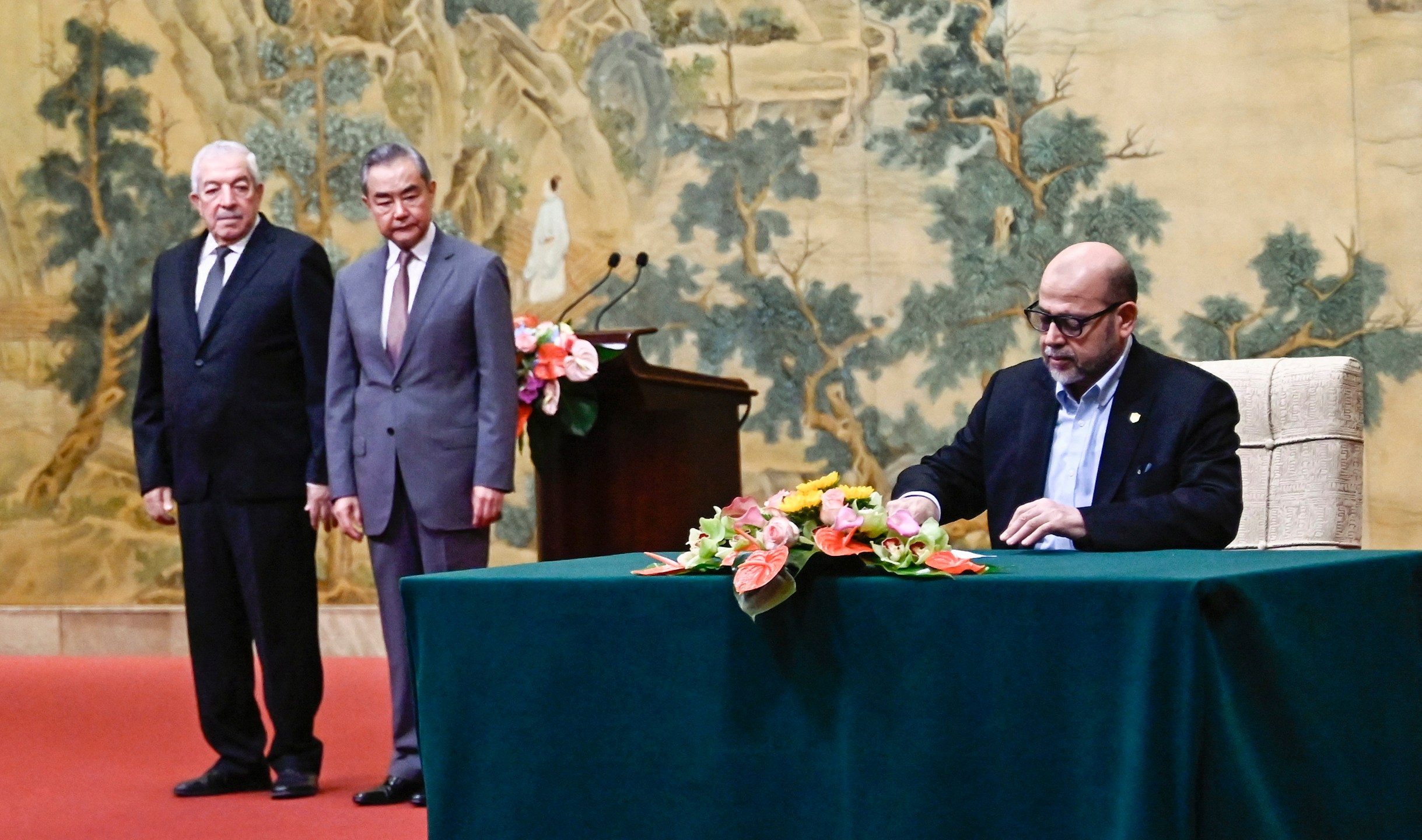 Mussa Abu Marzuk, a senior member of Hamas, right, signs a document as China's Foreign Minister Wang Yi, second left, and Mahmoud al-Aloul, vice chairman of Fatah, look on during an event hosting the Palestinian factions to meet at the Diaoyutai State Guesthouse in Beijing, Tuesday, July 23, 2024. (Pedro Pardo/Pool Photo via AP)