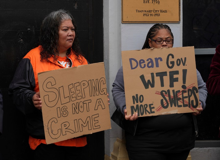 Activists hold signs at a news conference opposing Mayor London Breed's crackdown on homeless encampments in San Francisco, Tuesday, July 30, 2024. Police will start clearing out homeless residents who have refused to move from public areas under new policies. (AP Photo/Terry Chea)