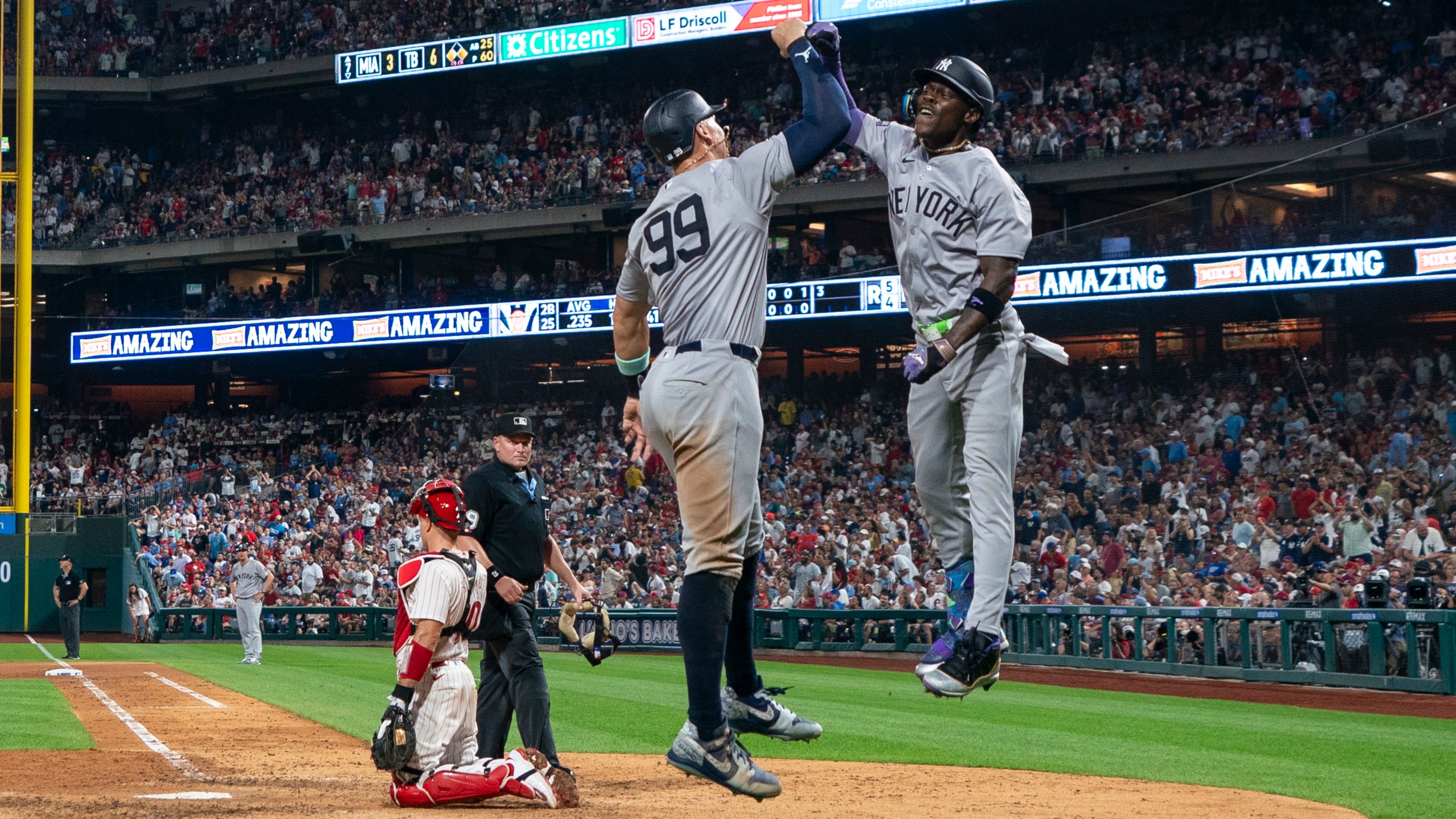 New York Yankees' Jazz Chisholm Jr., right, celebrates his three-run home run with Aaron Judge, center, as Philadelphia Phillies catcher J.T. Realmuto, left, looks on during the seventh inning of a baseball game, Tuesday, July 30, 2024, in Philadelphia. (AP Photo/Chris Szagola)
