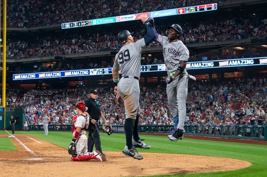 New York Yankees' Jazz Chisholm Jr., right, celebrates his three-run home run with Aaron Judge, center, as Philadelphia Phillies catcher J.T. Realmuto, left, looks on during the seventh inning of a baseball game, Tuesday, July 30, 2024, in Philadelphia. (AP Photo/Chris Szagola)