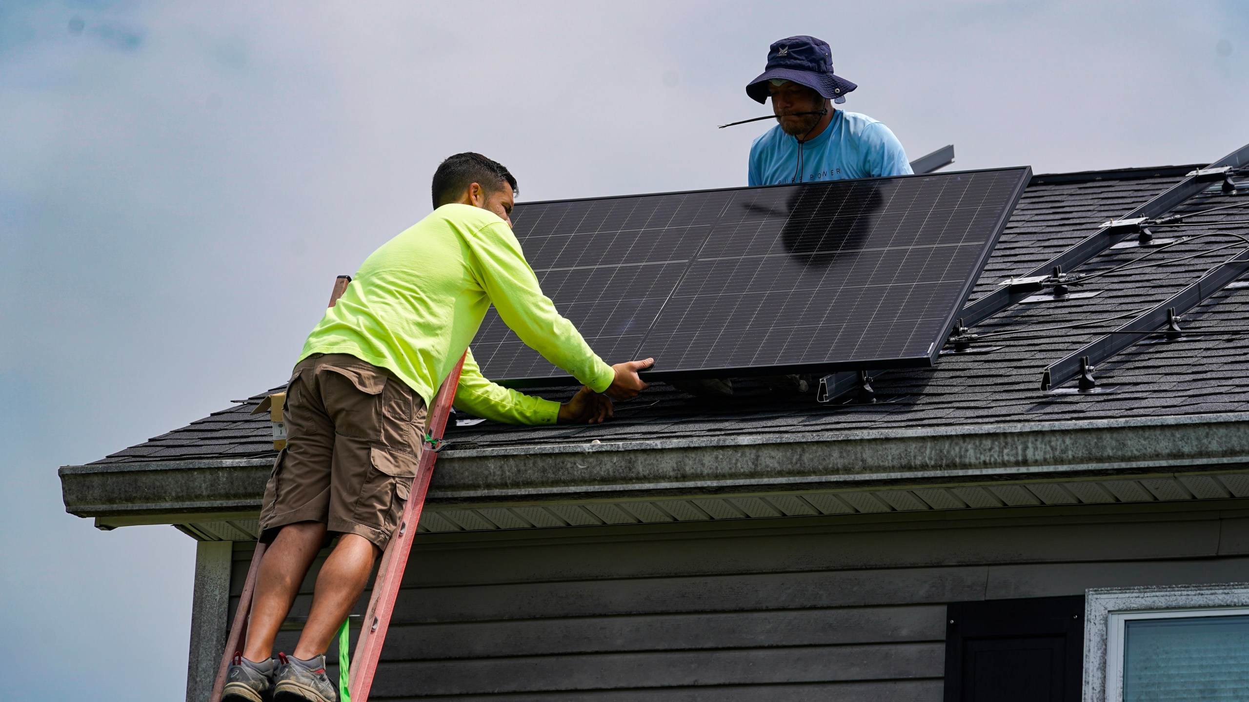 FILE - Brian Hoeppner, right, and Nicholas Hartnett, owner of Pure Power Solar, install a solar panel on the roof of a home in Frankfort, Ky., July 17, 2023. (AP Photo/Michael Conroy, File)