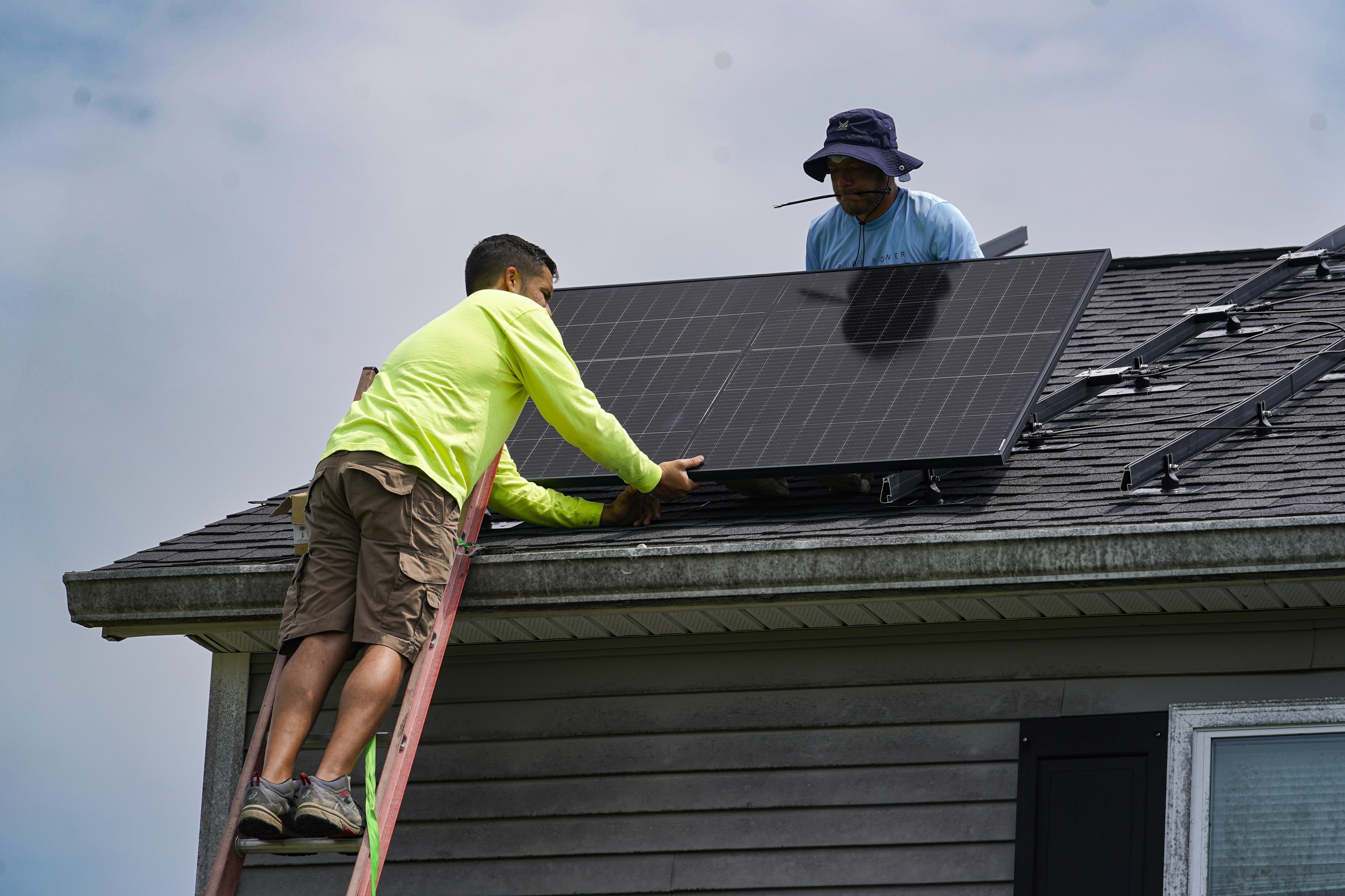 FILE - Brian Hoeppner, right, and Nicholas Hartnett, owner of Pure Power Solar, install a solar panel on the roof of a home in Frankfort, Ky., July 17, 2023. (AP Photo/Michael Conroy, File)