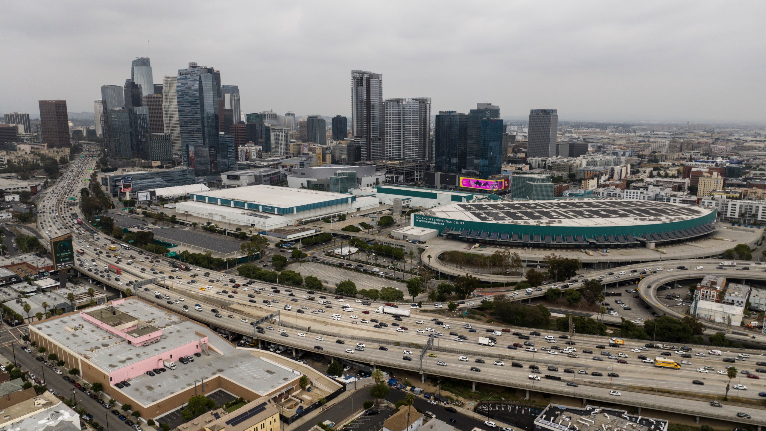 This aerial view shows traffic moving along the 110 Freeway past the Los Angeles Convention Center in Los Angeles, Tuesday, Sept. 5, 2023. As the Olympics close in Paris, Los Angeles will take the torch. The city will become the third city to host the games three times as it adds 2028 to the locally legendary years of 1932 and 1984. (AP Photo/Jae C. Hong, File)