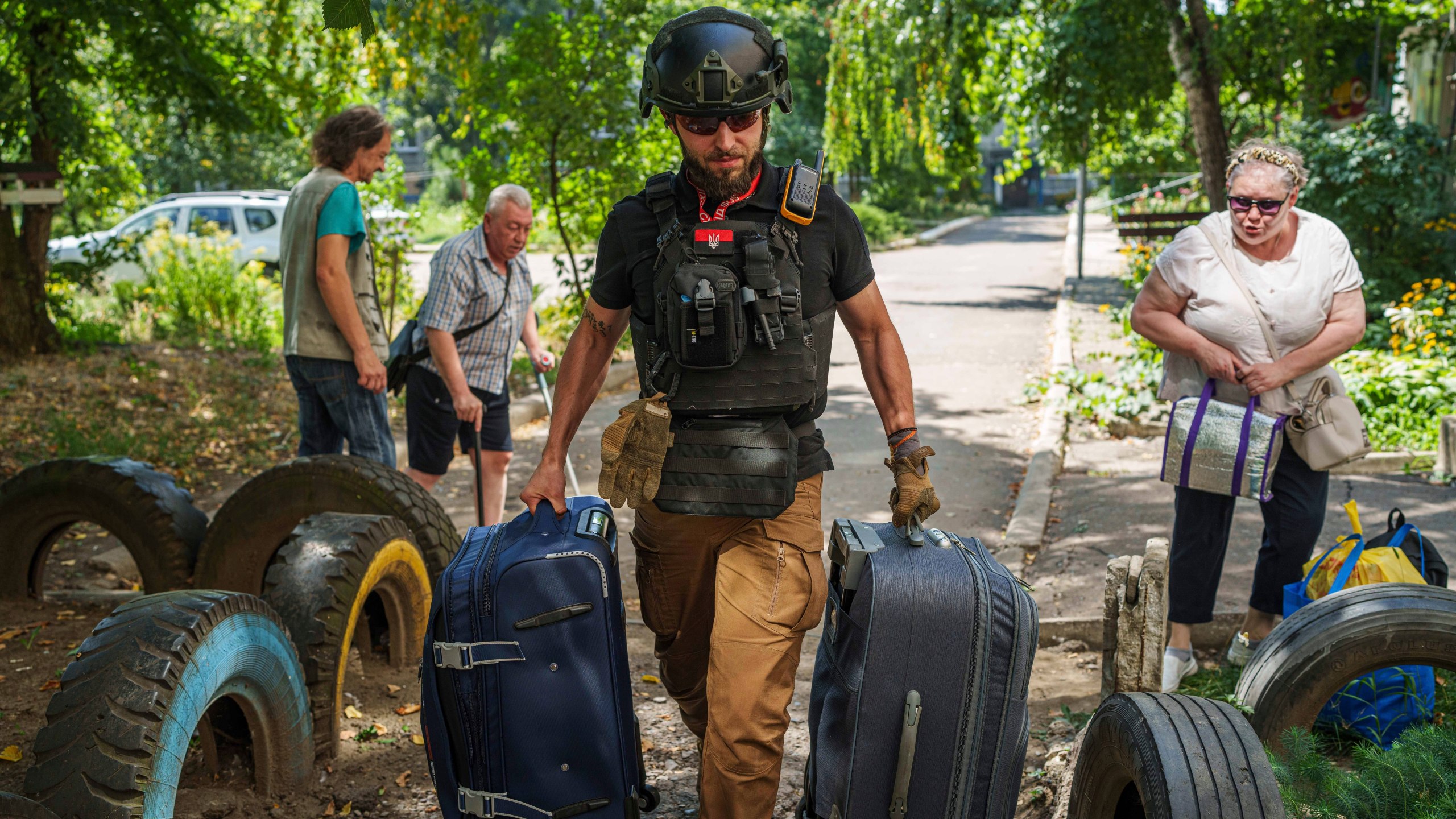A volunteer on East SOS helps to carry bags of evacuees in Selidove, Donetsk region, Ukraine, Monday, August 19, 2024. Due to the advance of Russian troops, the war affects more and more new settlements to the west of the Donetsk region. Intensive shelling forced people to leave homes. (AP Photo/Evgeniy Maloletka)