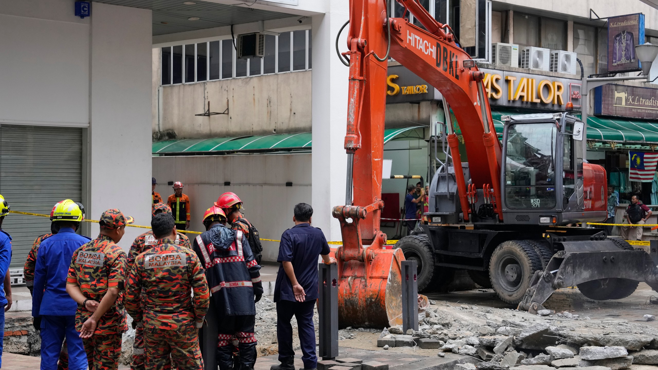 Fire and Rescue department use crane to dig a deep sinkhole after receiving reports that a woman has fallen into the sinkhole after a section of the sidewalk caved in Kuala Lumpur, Friday, Aug. 23, 2024. (AP Photo/Vincent Thian)