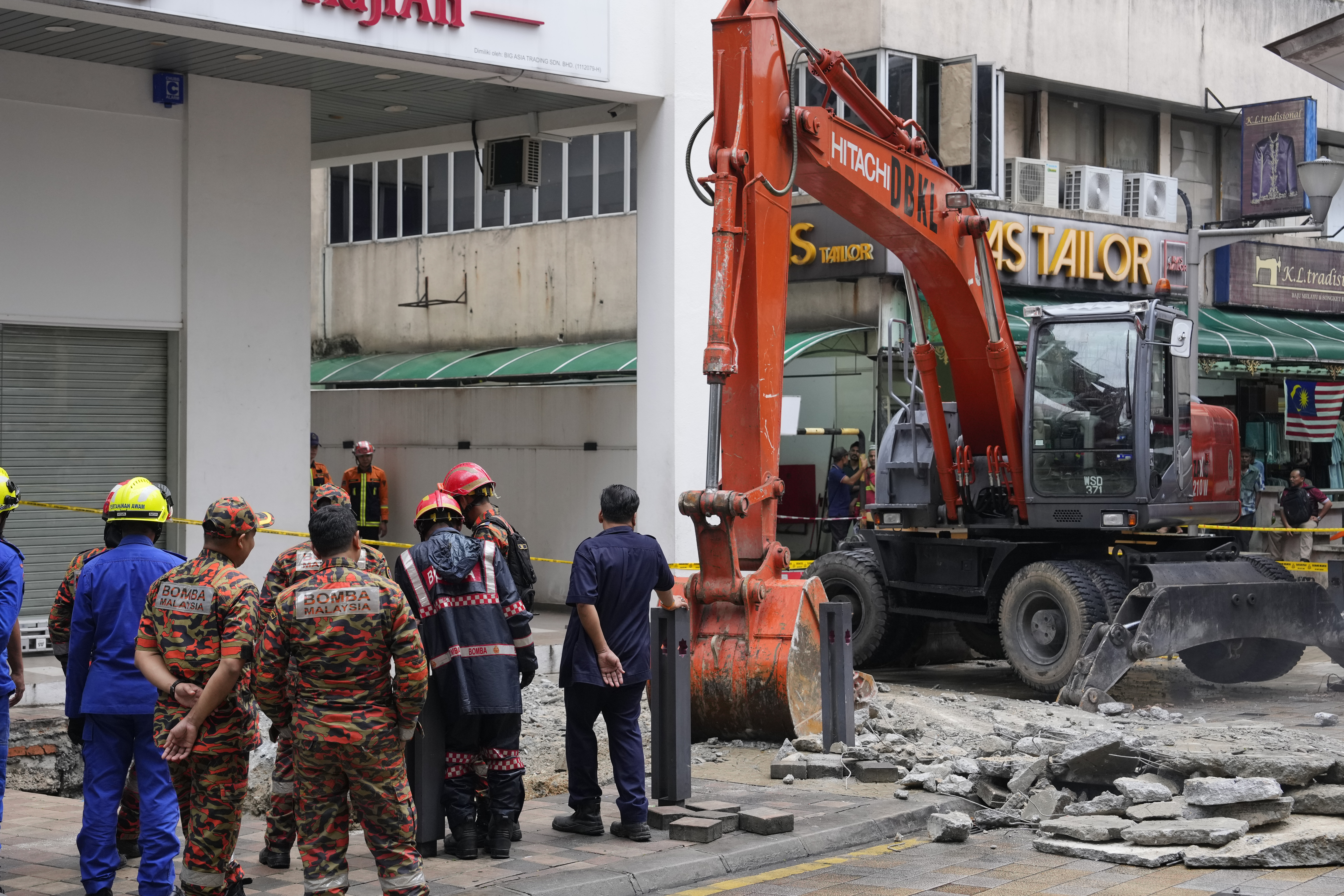 Fire and Rescue department use crane to dig a deep sinkhole after receiving reports that a woman has fallen into the sinkhole after a section of the sidewalk caved in Kuala Lumpur, Friday, Aug. 23, 2024. (AP Photo/Vincent Thian)