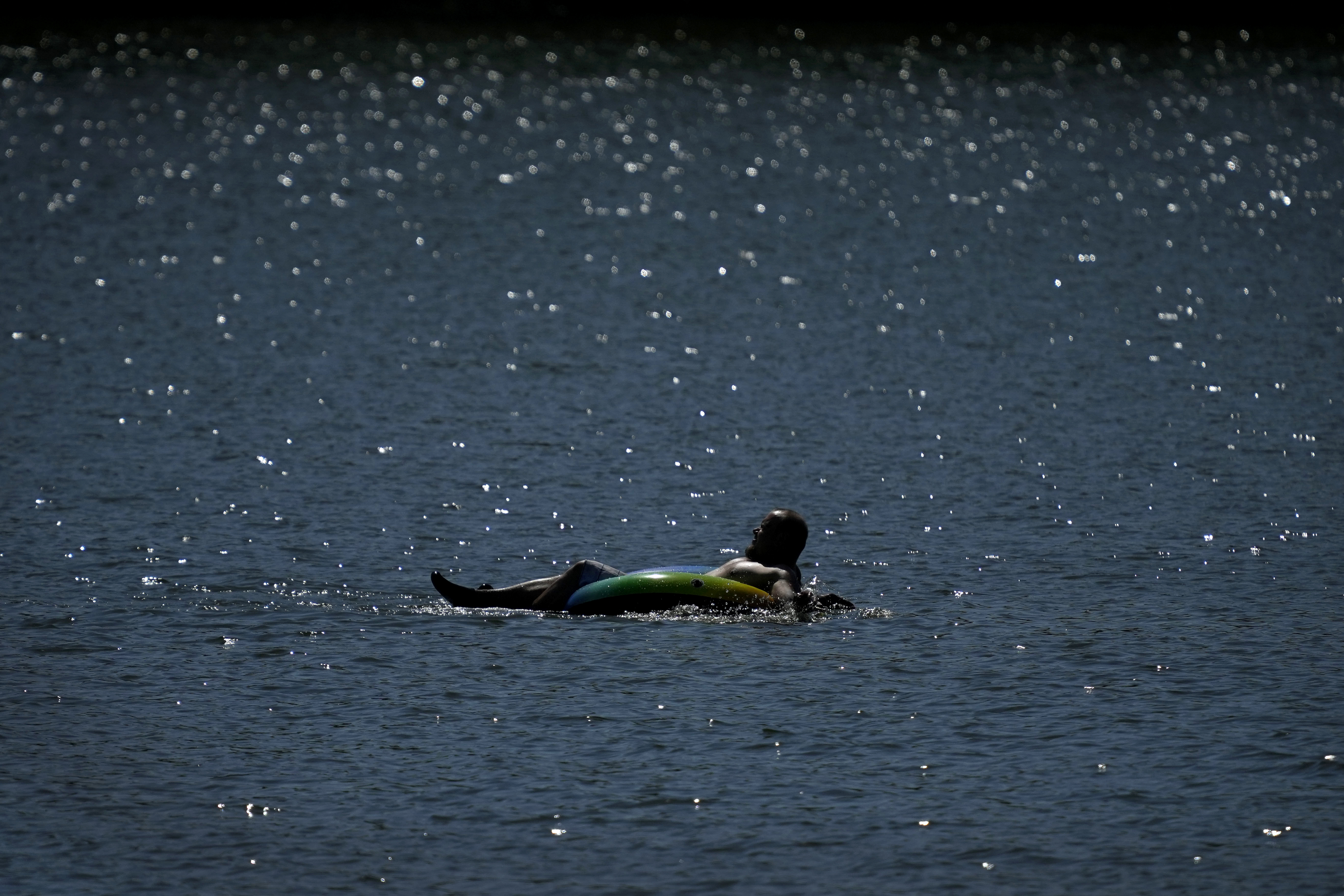 A tuber floats in the lake at Gray's Lake Park as the heat index tops 100 degrees, Monday, Aug. 26, 2024, in Des Moines, Iowa. (AP Photo/Charlie Neibergall)