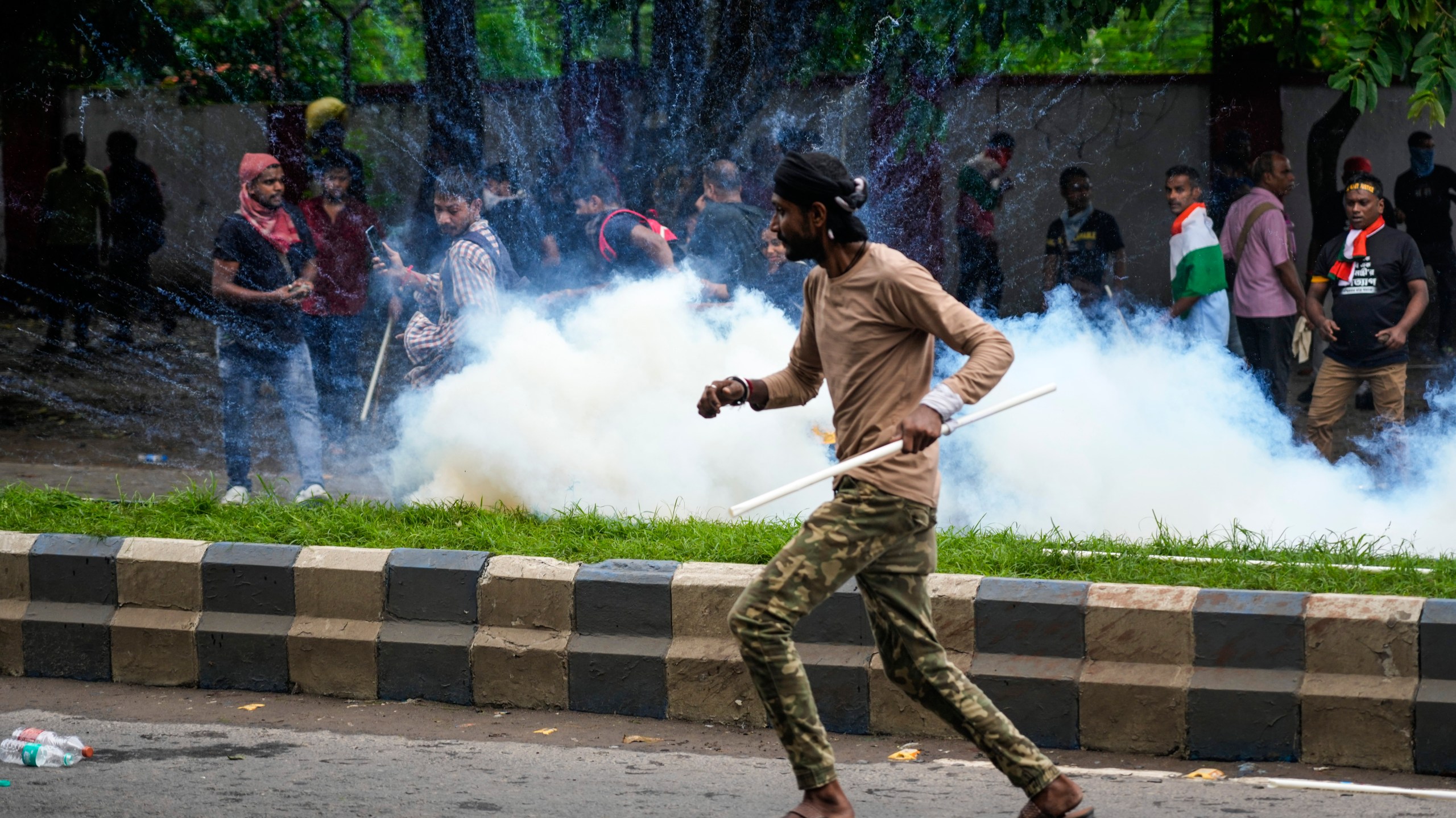 Protestors against the rape and murder of a resident doctor at a government hospital earlier this month, runs as police fire tear gas, in Kolkata, India, Tuesday, Aug. 27, 2024. (AP Photo/Bikas Das)