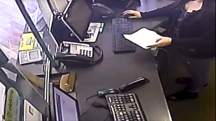 The suspect hands a note to the teller and pushes a brown papaer bag toward her before brandishing a weapon during an attempted robbery in Santa Ana on Aug. 7, 2024. (Santa Ana Police Department)