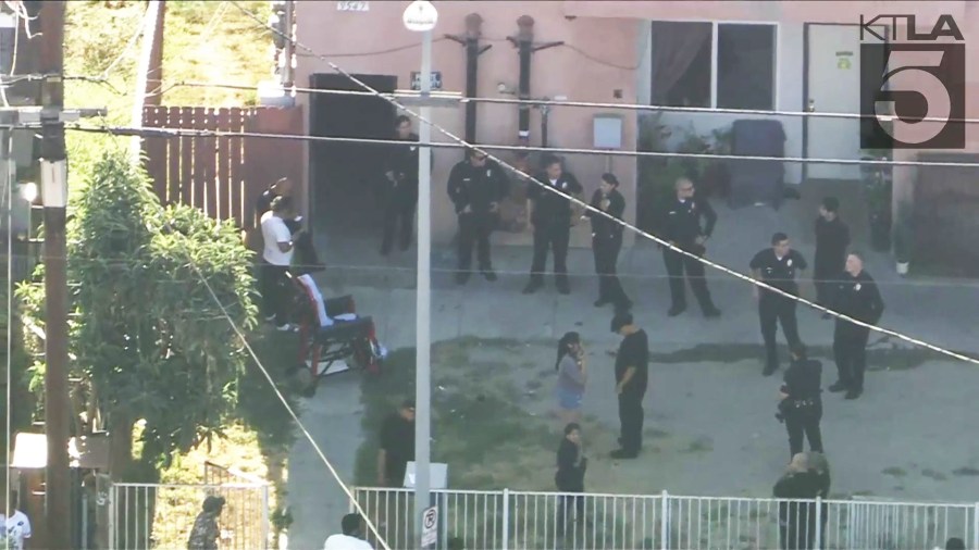 Officers interviewed bystanders who had gathered outside the apartment entrance on August 16, 2024. (KTLA)
