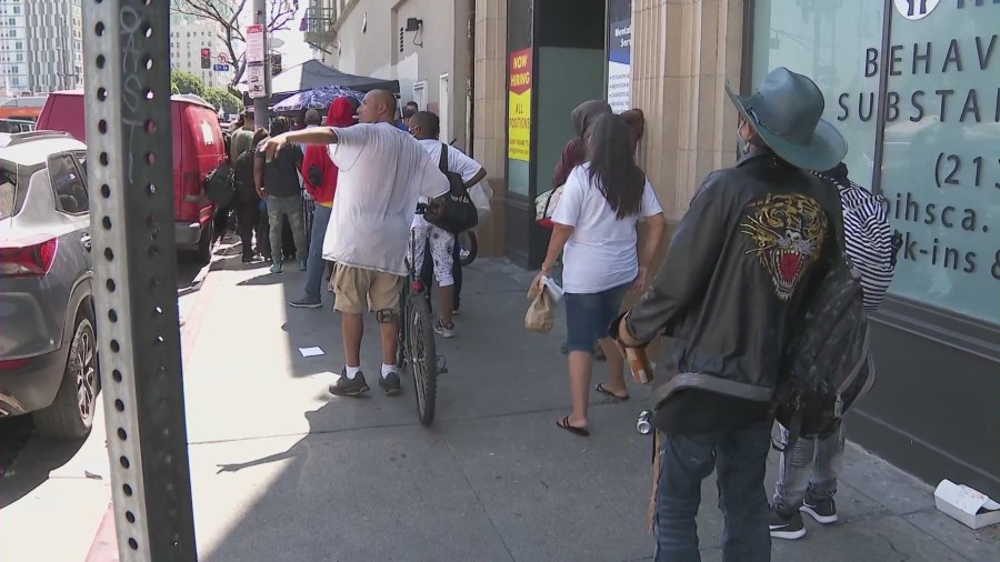 Long lines wrap around the block as hungry Skid Row residents await Chris Bailey's free meals. (KTLA)