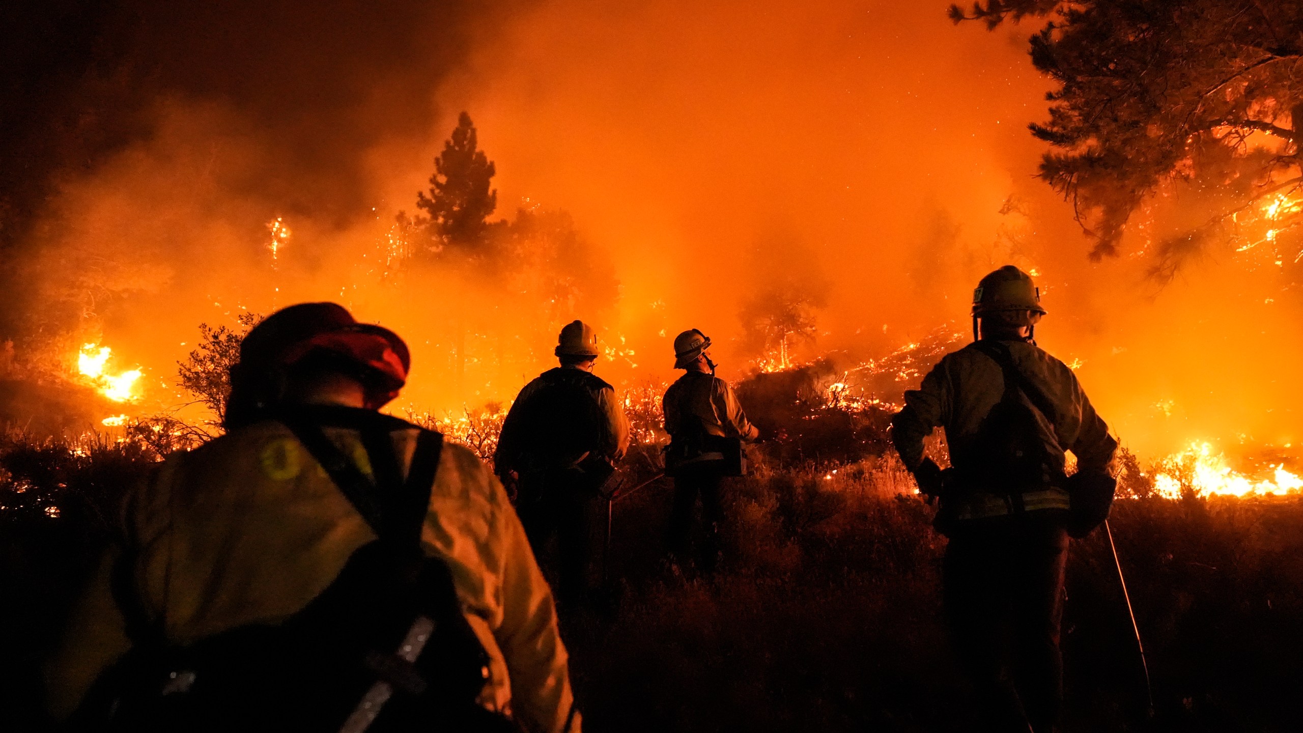 Firefighters watch as the Bridge Fire burns near homes in Wrightwood, Calif., Tuesday, Sept. 10, 2024. (AP Photo/Jae C. Hong)