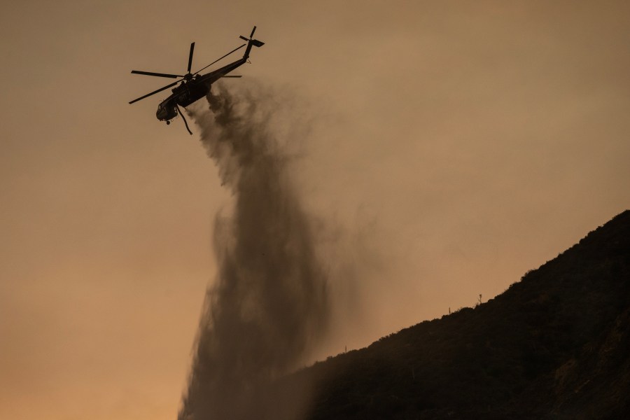 GLENDORA, CALIFORNIA - SEPTEMBER 9: A firefighting helicopter makes a water drop at the Bridge Fire on September 9, 2024 near Glendora, California. Heatwave conditions and steep slopes are fueling the expansion of the fire. (Photo by David McNew/Getty Images)