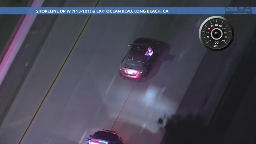 The passenger repeatedly sat on the windowsill while gesturing at officers and taking photos/video of the chase on his phone during the L.A. County pursuit on September 25, 2024. (KTLA)