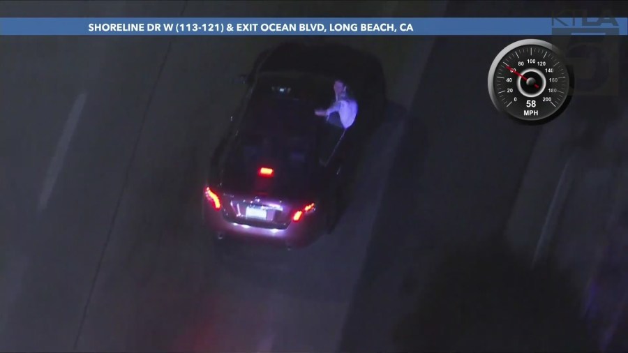 The passenger repeatedly sat on the windowsill while gesturing at officers and taking photos/video of the chase on his phone during the L.A. County pursuit on September 25, 2024. (KTLA)