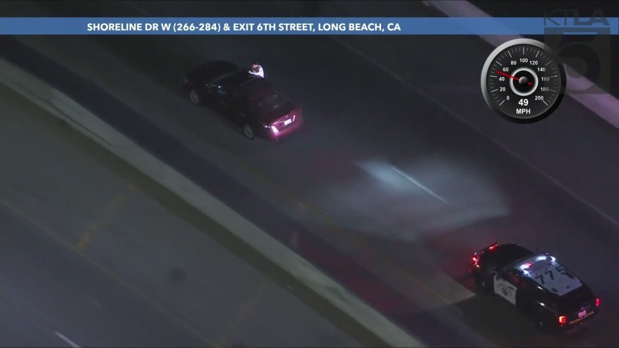 The passenger repeatedly sat on the windowsill while gesturing at officers and taking photos/video of the chase on his phone during the L.A. County pursuit on September 25, 2024. (KTLA)