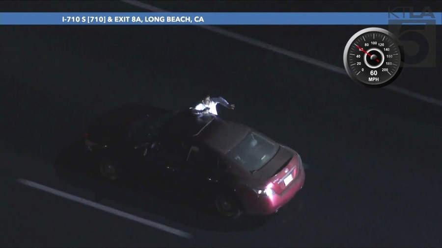 The passenger repeatedly sat on the windowsill while gesturing at officers and taking photos/video of the chase on his phone during the L.A. County pursuit on September 25, 2024. (KTLA)