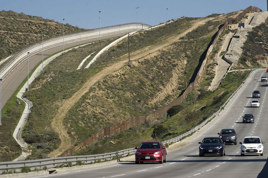Vehicles drive along a highway next to the border wall that separates the U.S. and Mexico in Tijuana, Mexico, on Thursday, Jan. 26, 2017. (David Maung/Bloomberg via Getty Images)