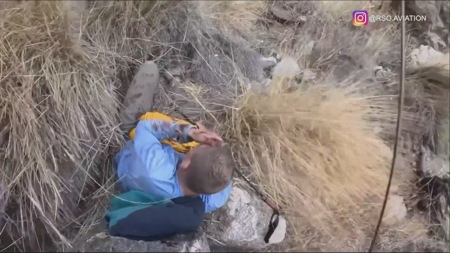 One hiker is seen injured and bloodied as rescuers airlift him from a rocky ravine to safety on Oct. 27, 2024. (@rsoaviation)