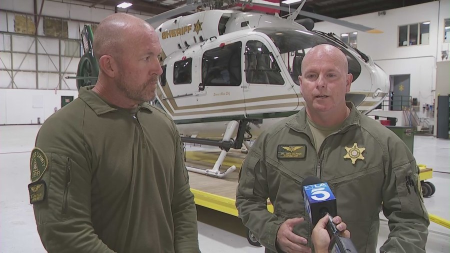 From left: Jason Tilley, a deputy rescue specialist EMT and Cpl. Mike Calhoun, the pilot involved in the rescue, speak to KTLA. (KTLA)