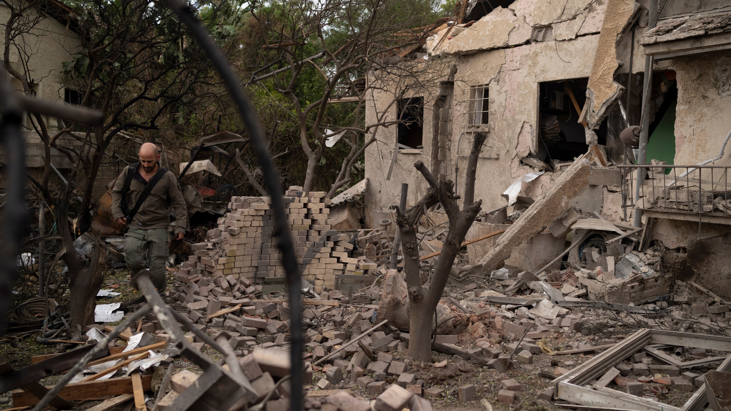 A member of the Israeli security forces inspects an impact site following a rocket fired from Lebanon hit an area in Rinatya, outskirts of Tel Aviv, Israel, Sunday, Nov. 24, 2024. (AP Photo/Leo Correa)