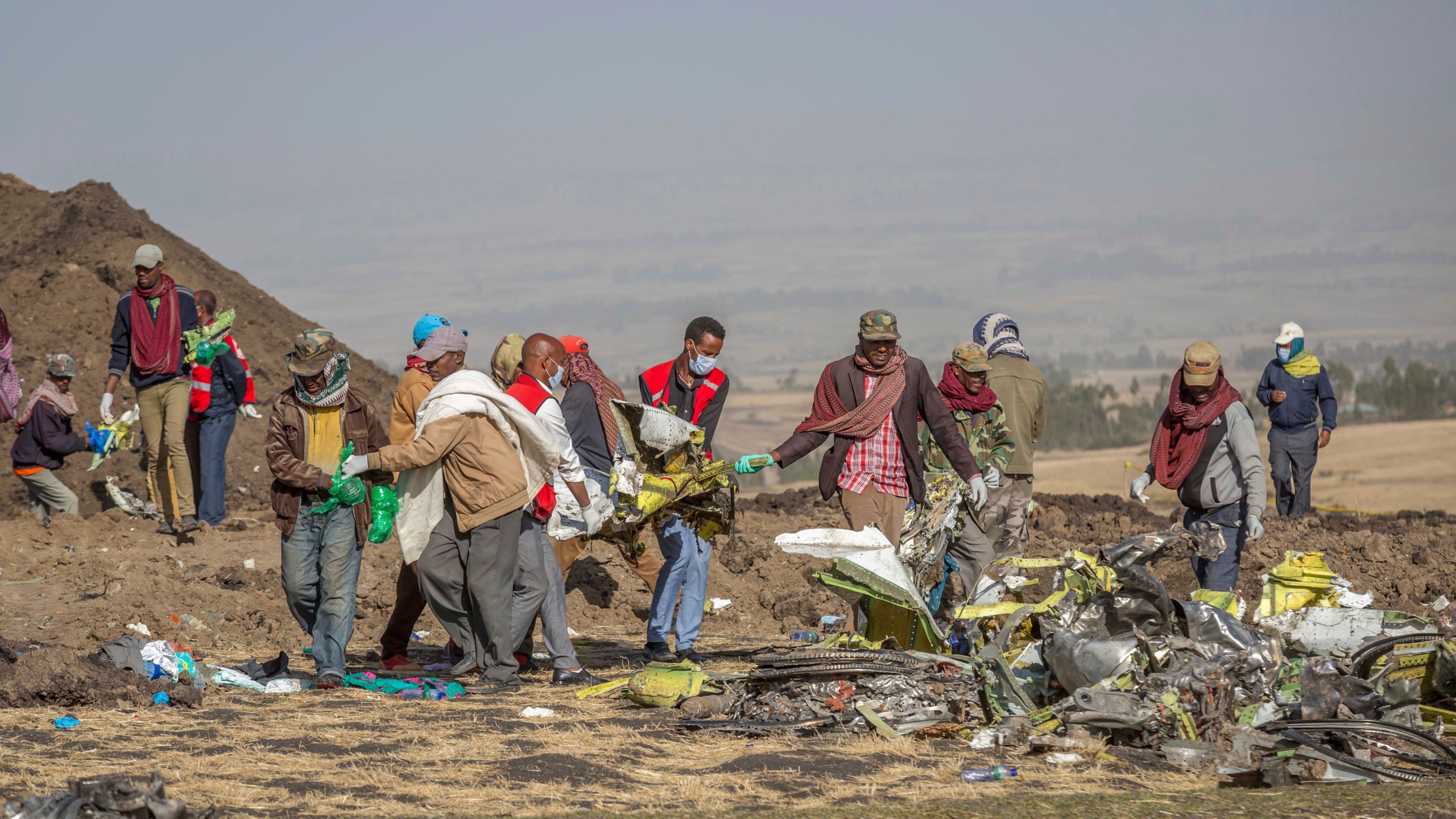 FILE - Debris is carried at the scene of an Ethiopian Airlines flight crash near Bishoftu, or Debre Zeit, south of Addis Ababa, Ethiopia, on March 11, 2019. A spokesman says Ethiopian Airlines has grounded all its Boeing 737 Max 8 aircraft as a safety precaution, following the crash of one of its planes in which 157 people were killed. (AP Photo/Mulugeta Ayene)
