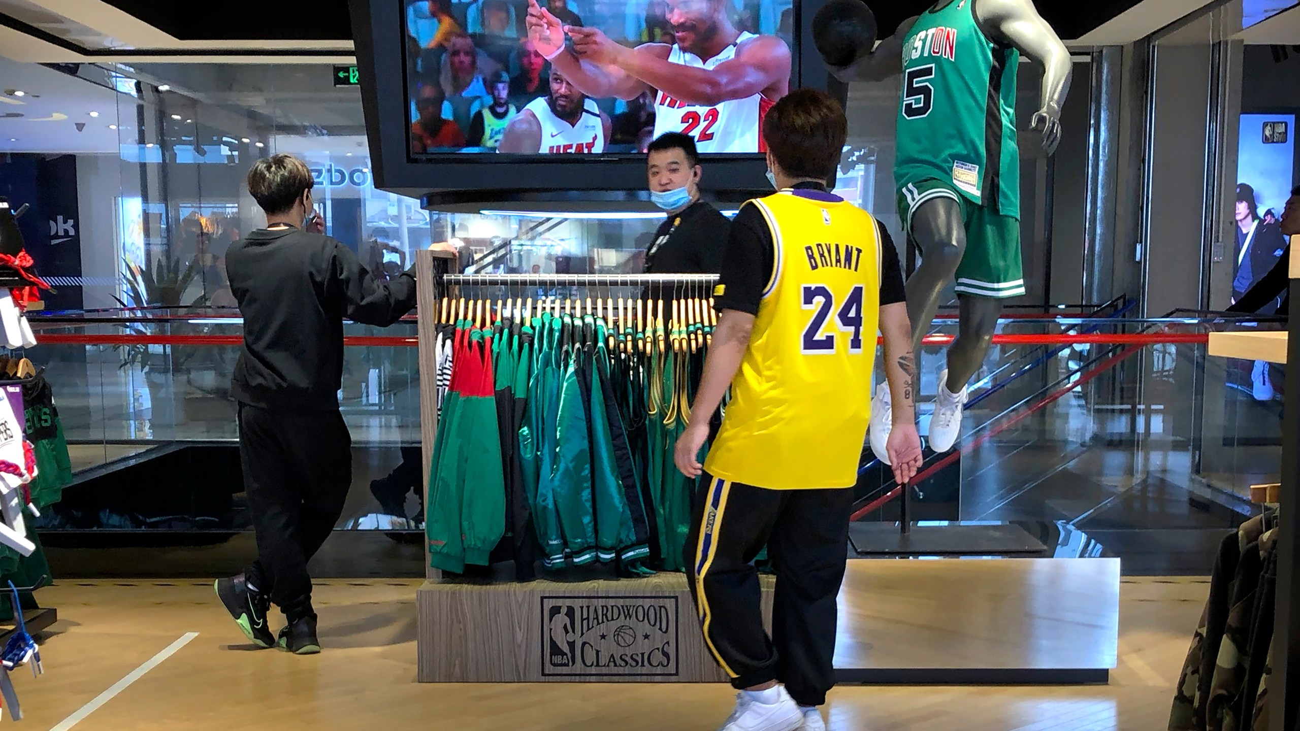 FILE - Employees watch a live broadcast of Game 5 of the NBA finals at an NBA store in Beijing, Oct. 10, 2020. (AP Photo/Mark Schiefelbein, File)
