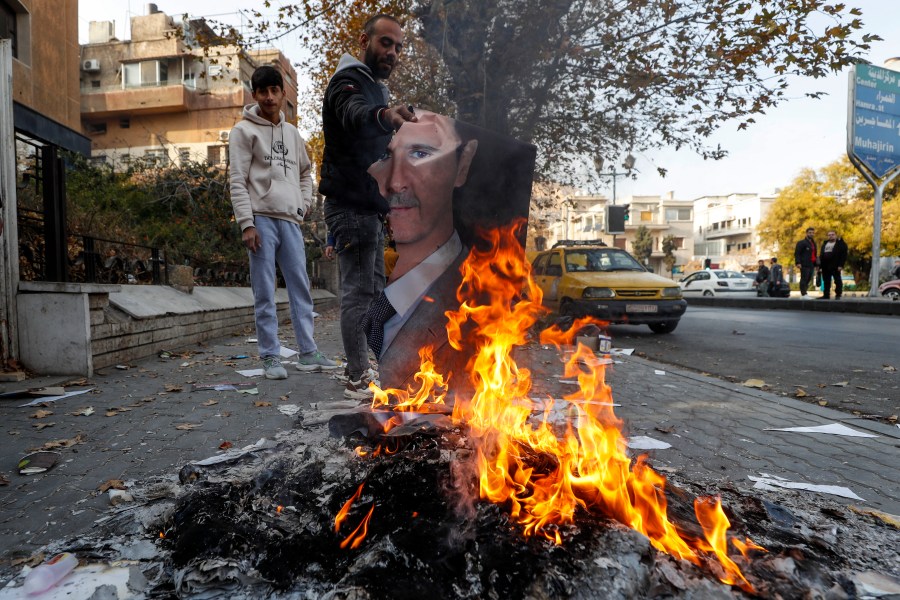 A Syrian man burns a picture of ousted Syrian President Bashar Assad in Damascus, Syria, Monday, Dec. 9, 2024. (AP Photo/Omar Sanadiki)