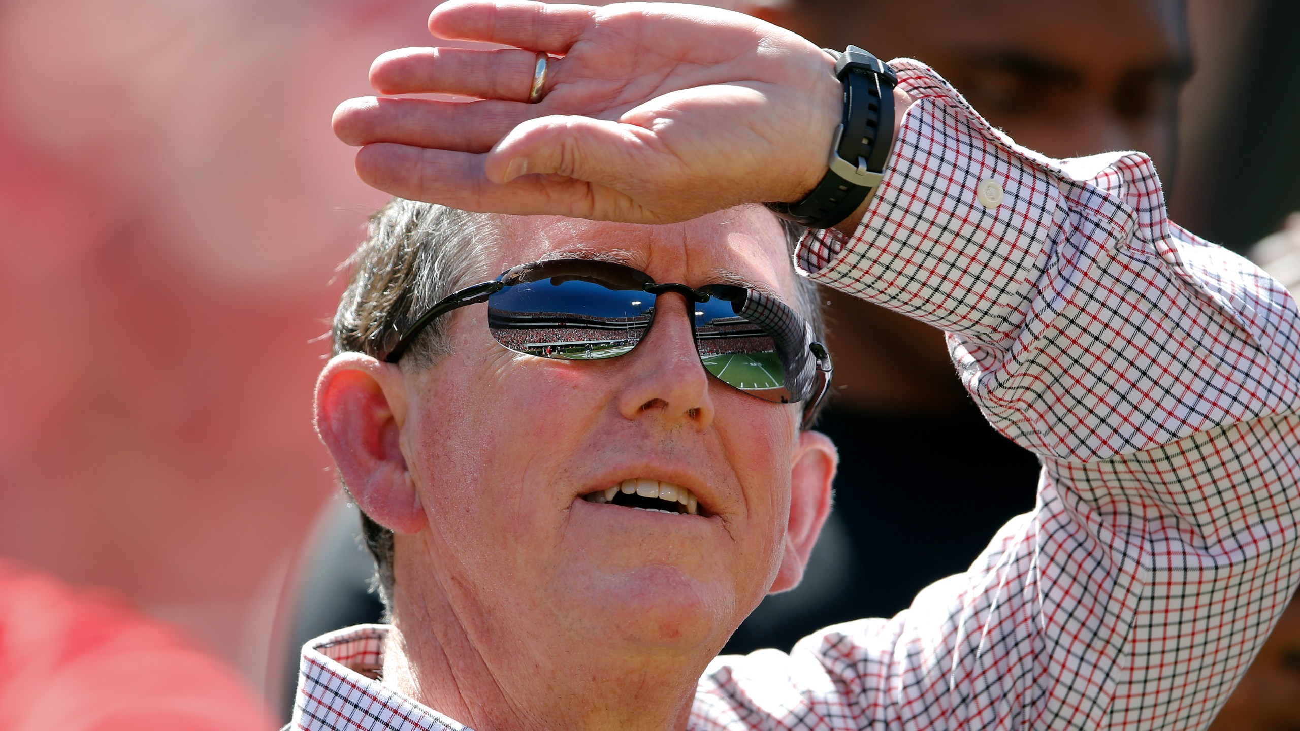 FILE - Sanford Stadium is reflected in Georgia athletic director Greg McGarity's sunglasses as he watches a pregame performance by rapper Ludacris before Georgia's spring intrasquad NCAA college football game Saturday, April 16, 2016, in Athens, Ga. (AP Photo/John Bazemore, File)