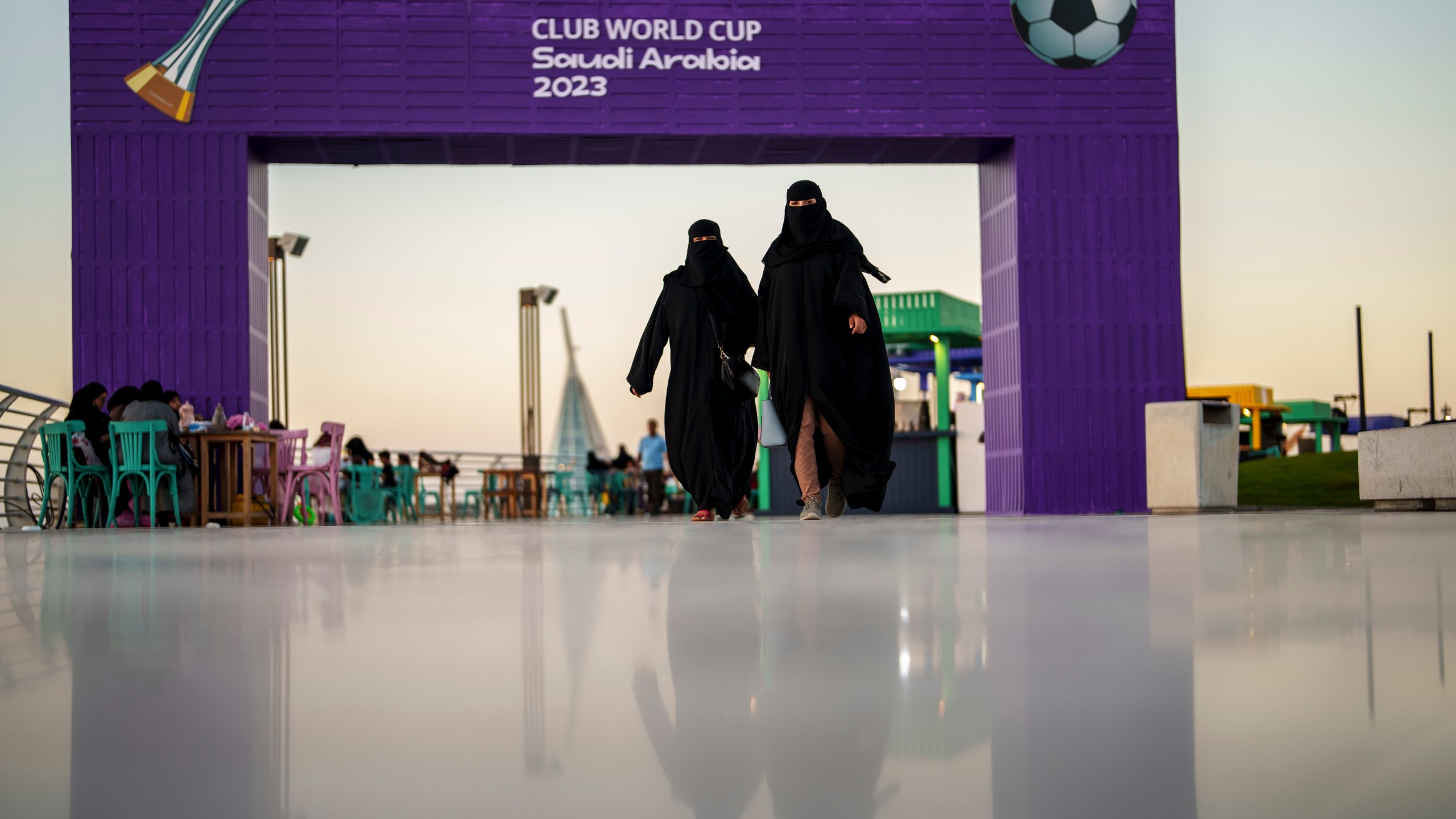 FILE - Women walk in front of a fan zone during the Soccer Club World Cup at the Jeddah Corniche in Jeddah, Saudi Arabia, Wednesday, Dec 13, 2023. (AP Photo/Manu Fernandez, File)