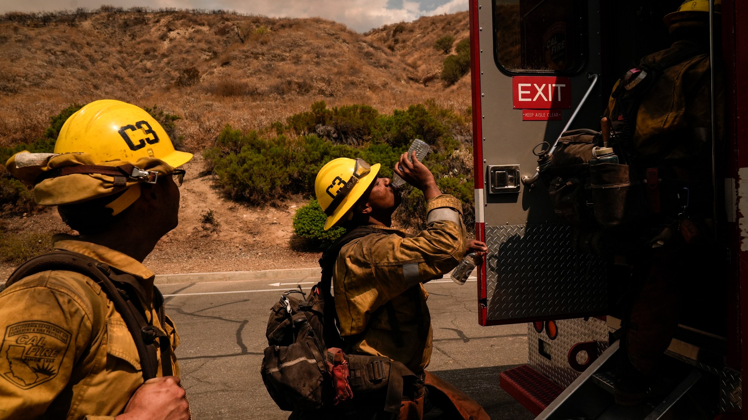FILE - Firefighter Geo Mulongo, center, finishes his water while taking a break during the Line Fire in Highland, Calif., Sept. 6, 2024. (AP Photo/Jae C. Hong, File)