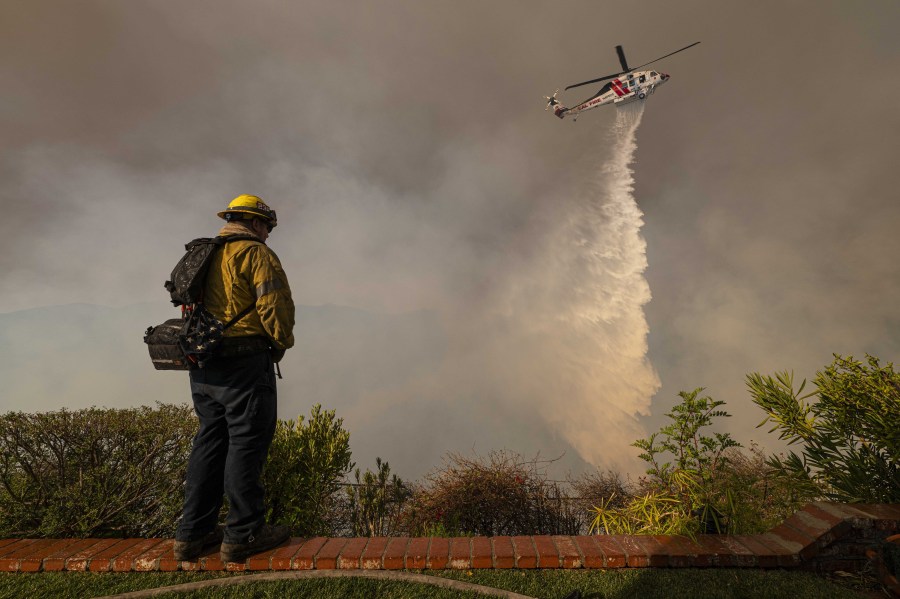 LOS ANGELES, USA - JANUARY 11: A Monterey County Firefighter watch as a LA County helicopter comes in to make a water drop on the Palisade Fire. (Photo by Jon Putman/Anadolu via Getty Images)