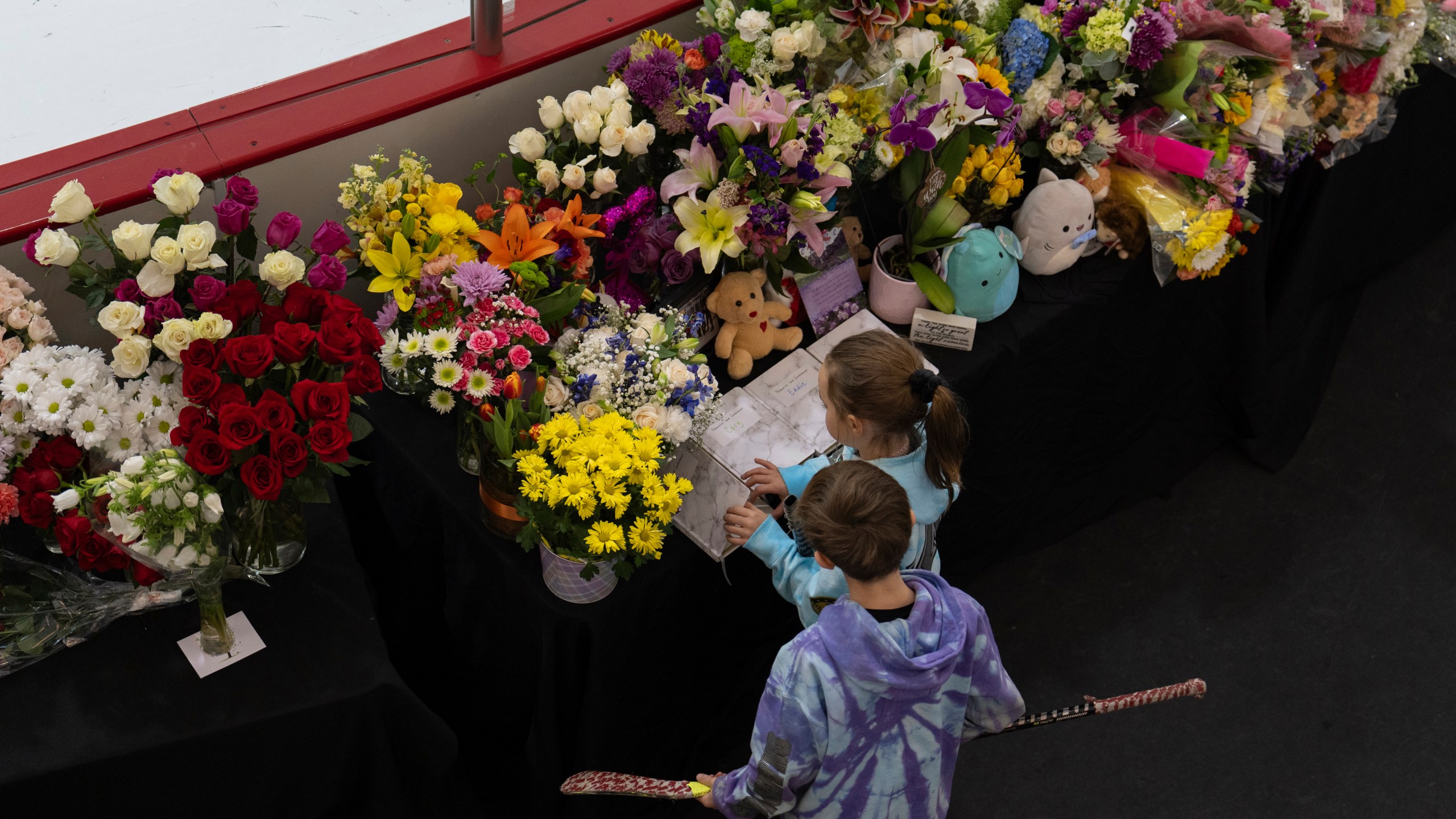 Young skates visit a memorial along the boards at MedStar Capitals Iceplex Sunday, Feb. 2, 2025, in Arlington, Va., for the figure skaters who were among the 67 victims of a mid-air collision between an Army helicopter and an American Airlines flight from Kansas. (AP Photo/Carolyn Kaster)