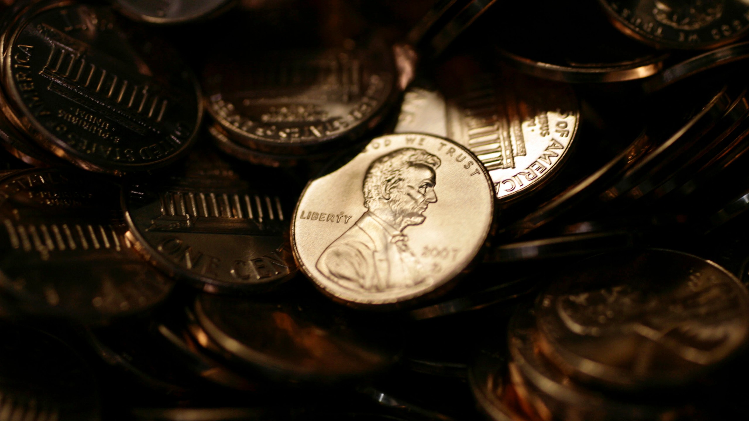 FILE - A lone penny is illuminated in a bin of completed pennies at the U.S. Mint in Denver, Aug. 15, 2007. (AP Photo/David Zalubowski)