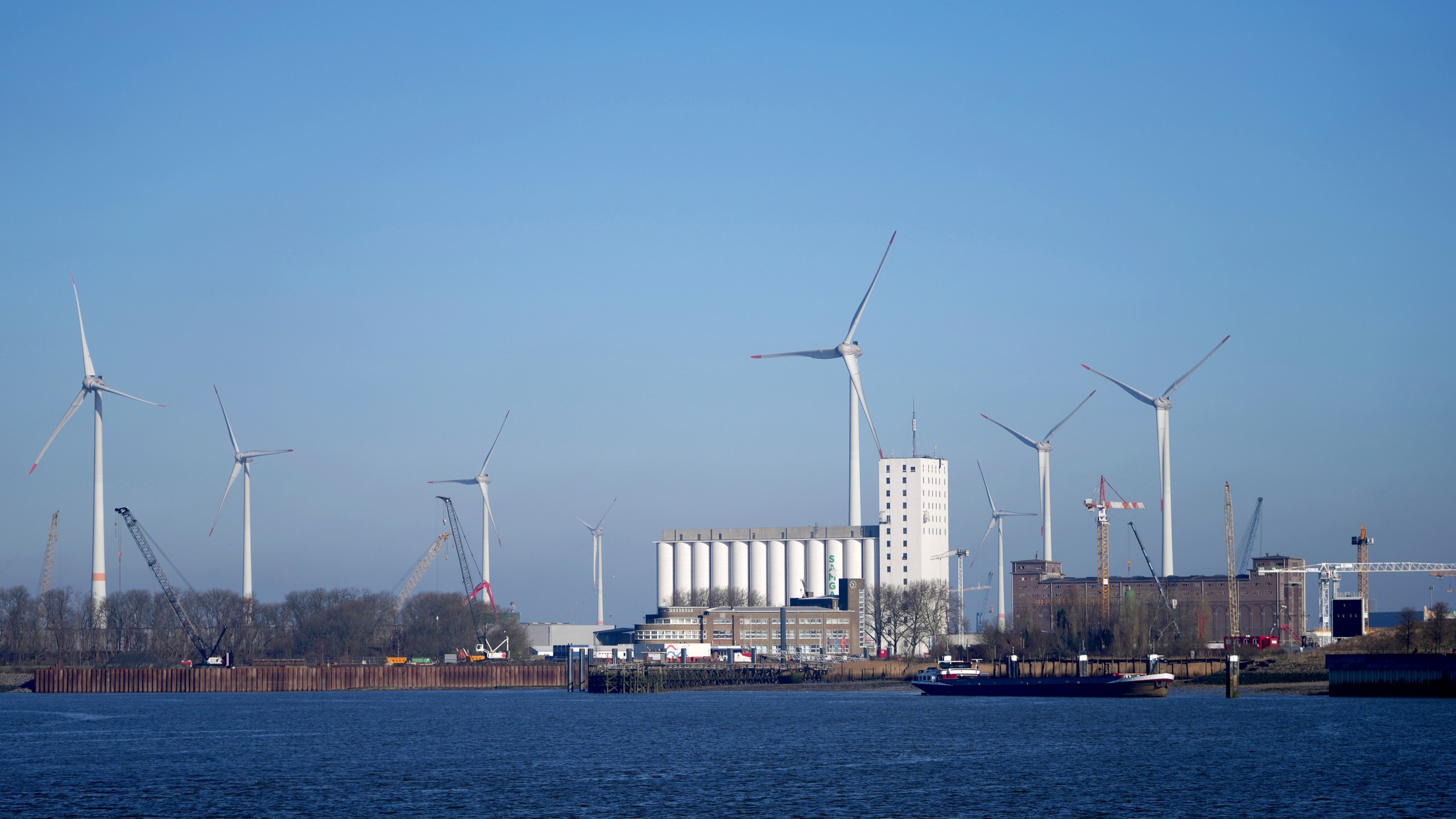 Wind turbines in front of industrial businesses along the River Scheldt in Antwerp, Belgium, Wednesday, Feb. 26, 2025. (AP Photo/Virginia Mayo)