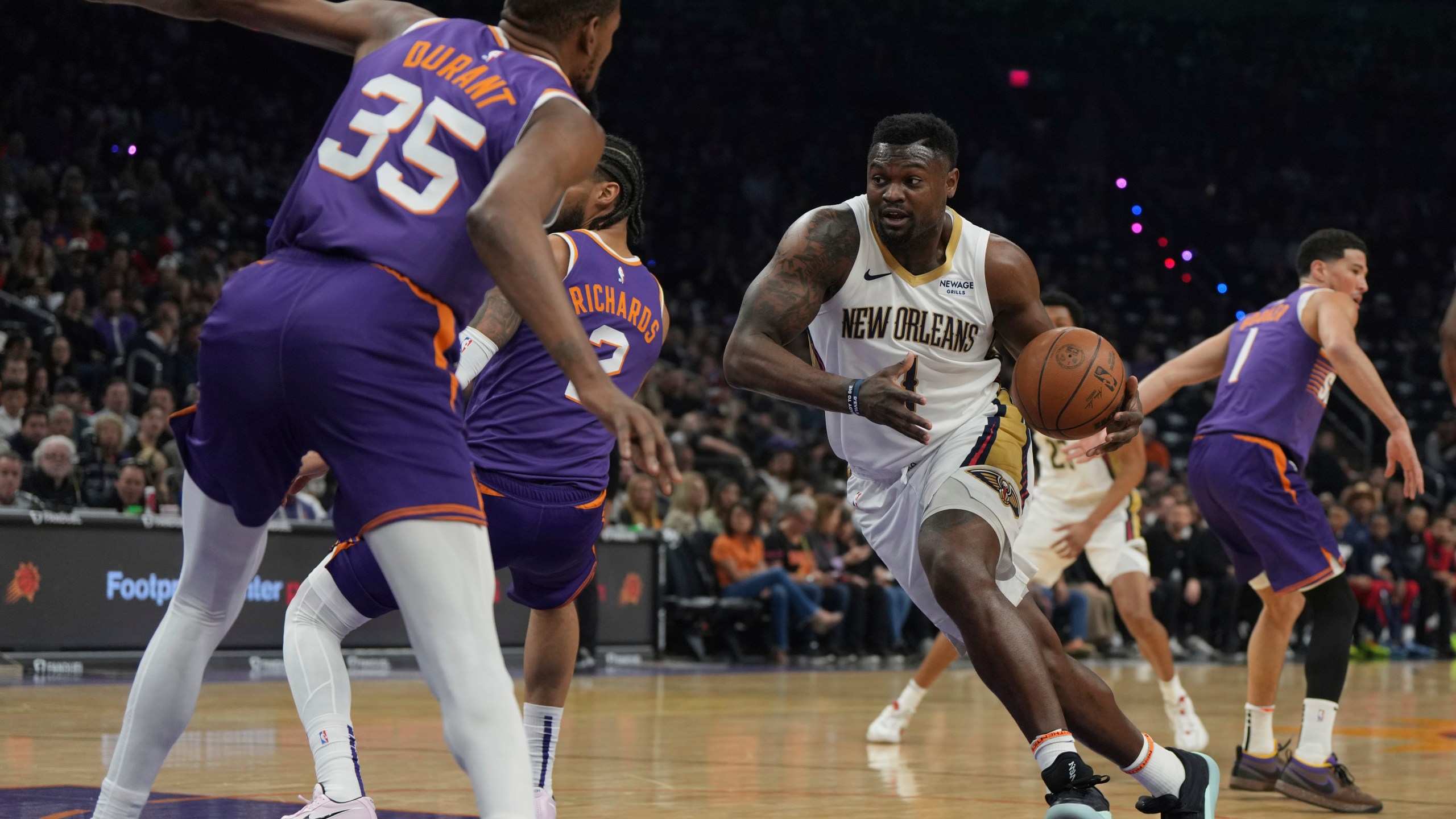 New Orleans Pelicans forward Zion Williamson (1) drives on Phoenix Suns center Nick Richards (2) and forward Kevin Durant during the first half of an NBA basketball game, Thursday, Feb. 27, 2025, in Phoenix. (AP Photo/Rick Scuteri)