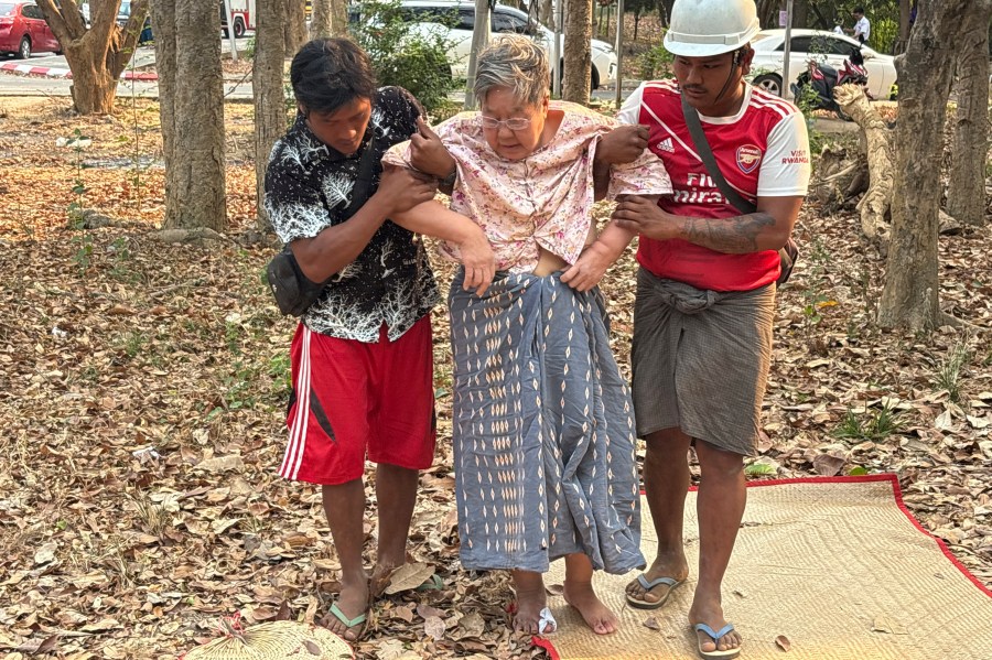Rescue workers help an injured women who was trapped under a building Friday, March 28, 2025, in Naypyitaw, Myanmar. (AP Photo/Aung Shine Oo)