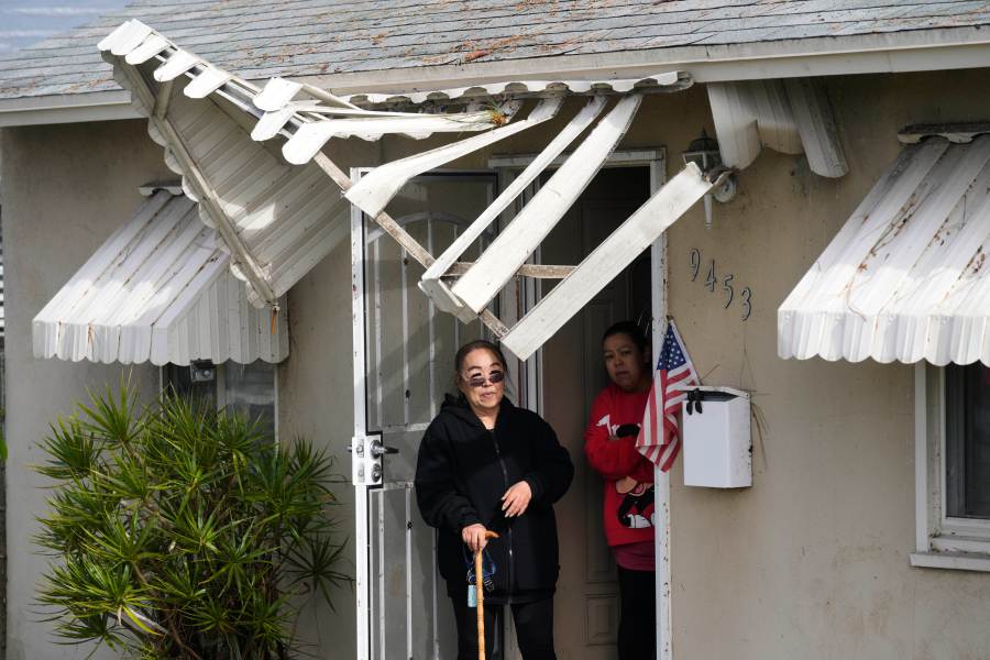 Resident Nicole Hiromoto, in black, stands under a damaged awning with Susie Gonzales, after a tornado passed through on Thursday, March 13, 2025, in Pico Rivera, Calif. (AP Photo/Damian Dovarganes)