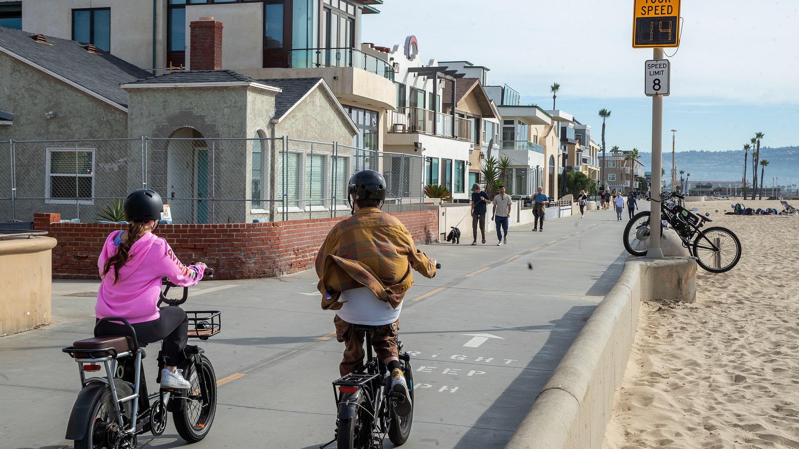 People ride an e-bike on the Strand in Hermosa Beach, going 14 mph, which is over the posted speed limit of 8 mph. In Hermosa Beach, it's against city code to use electric power on the Strand, but many e-bike riders do so anyway. (Mel Melcon / Los Angeles Times via Getty Images)