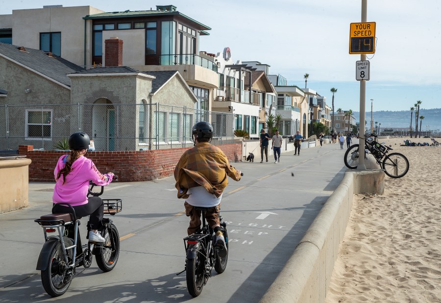 People ride an e-bike on the Strand in Hermosa Beach, going 14 mph, which is over the posted speed limit of 8 mph. In Hermosa Beach, it's against city code to use electric power on the Strand, but many e-bike riders do so anyway. (Mel Melcon / Los Angeles Times via Getty Images)