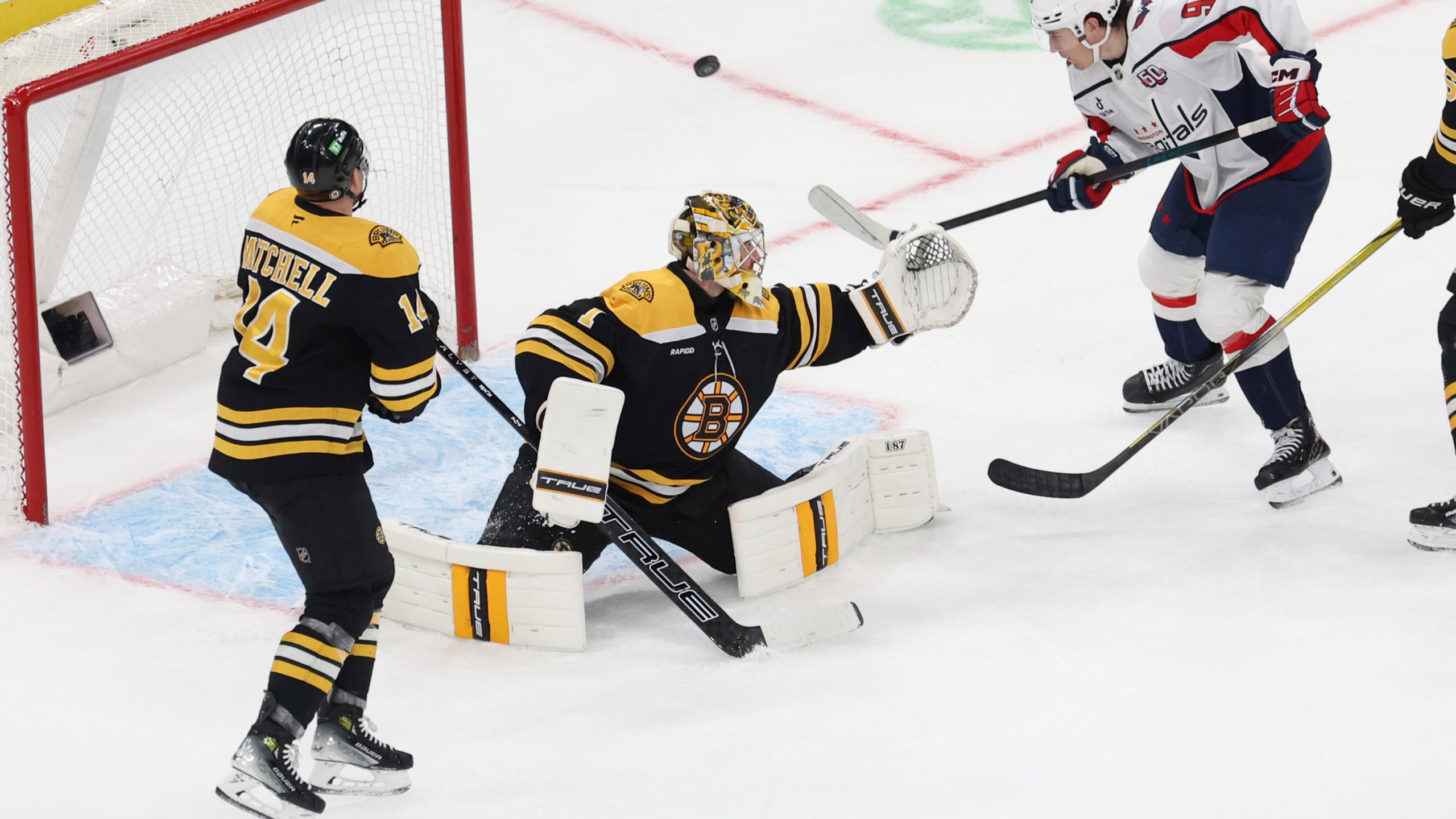 Washington Capitals right wing Ryan Leonard (9) comes up short on a goal as Boston Bruins defenseman Ian Mitchell (14) and goaltender Jeremy Swayman (1) defend the net during the third period of an NHL hockey game, Tuesday, April 1, 2025, in Boston. (AP Photo/Mark Stockwell)