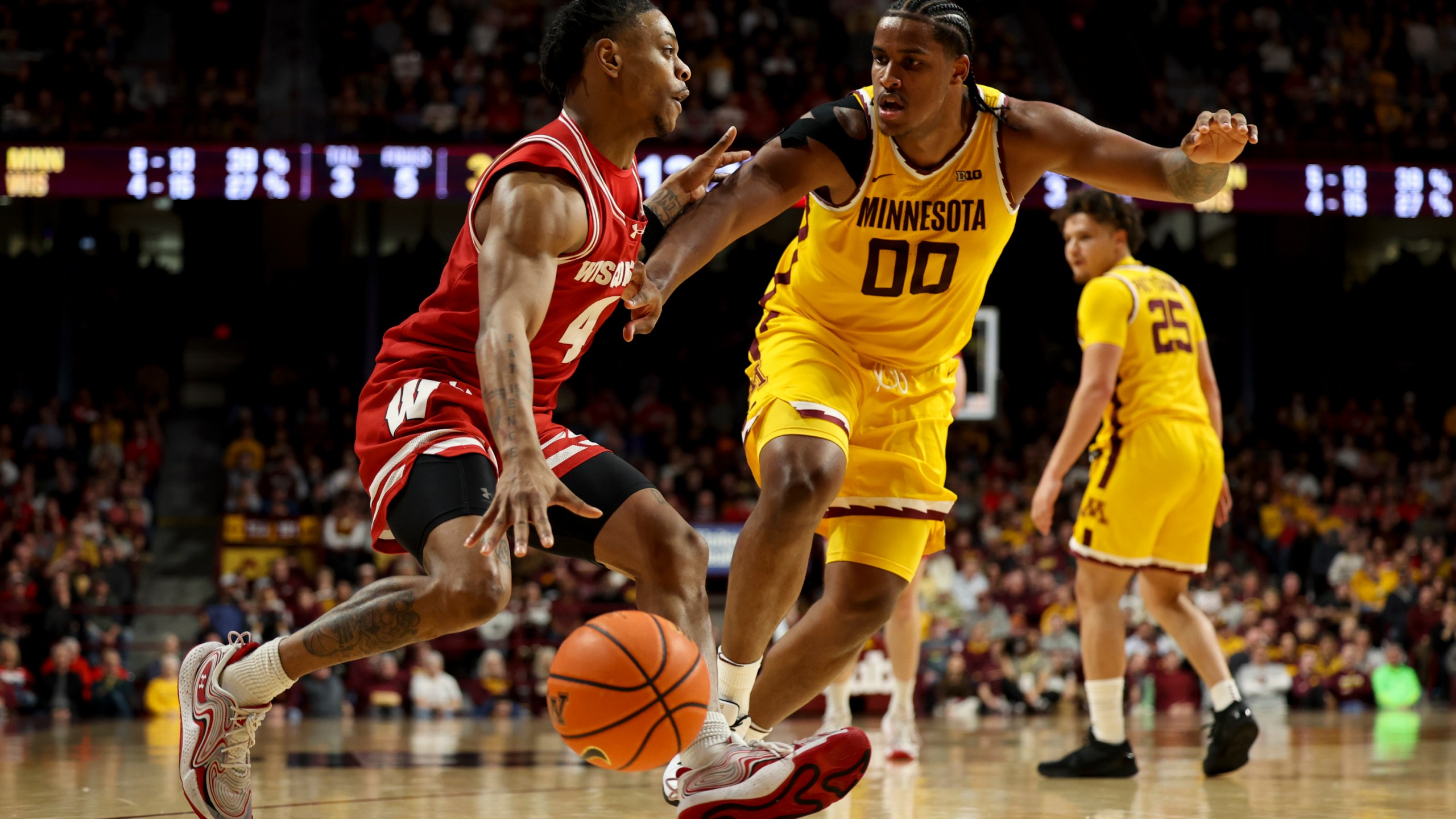 Wisconsin guard Kamari McGee (4) drives toward the hoop while Minnesota forward Frank Mitchell (00) defends during the second half of an NCAA college basketball game, Wednesday, March 5, 2025, in Minneapolis. (AP Photo/Ellen Schmidt)
