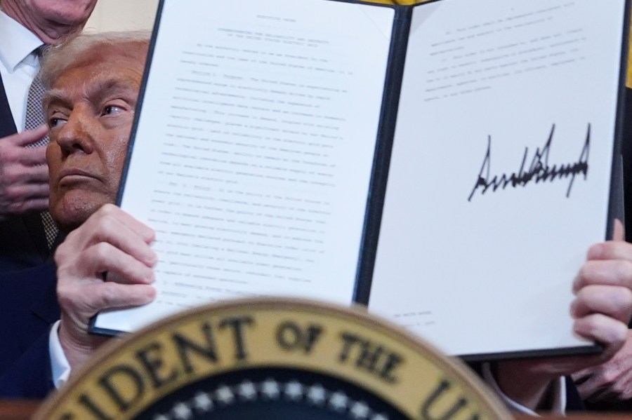 President Donald Trump holds a signed executive order during an event in the East Room of the White House, Tuesday, April 8, 2025, in Washington. (AP Photo/Evan Vucci)