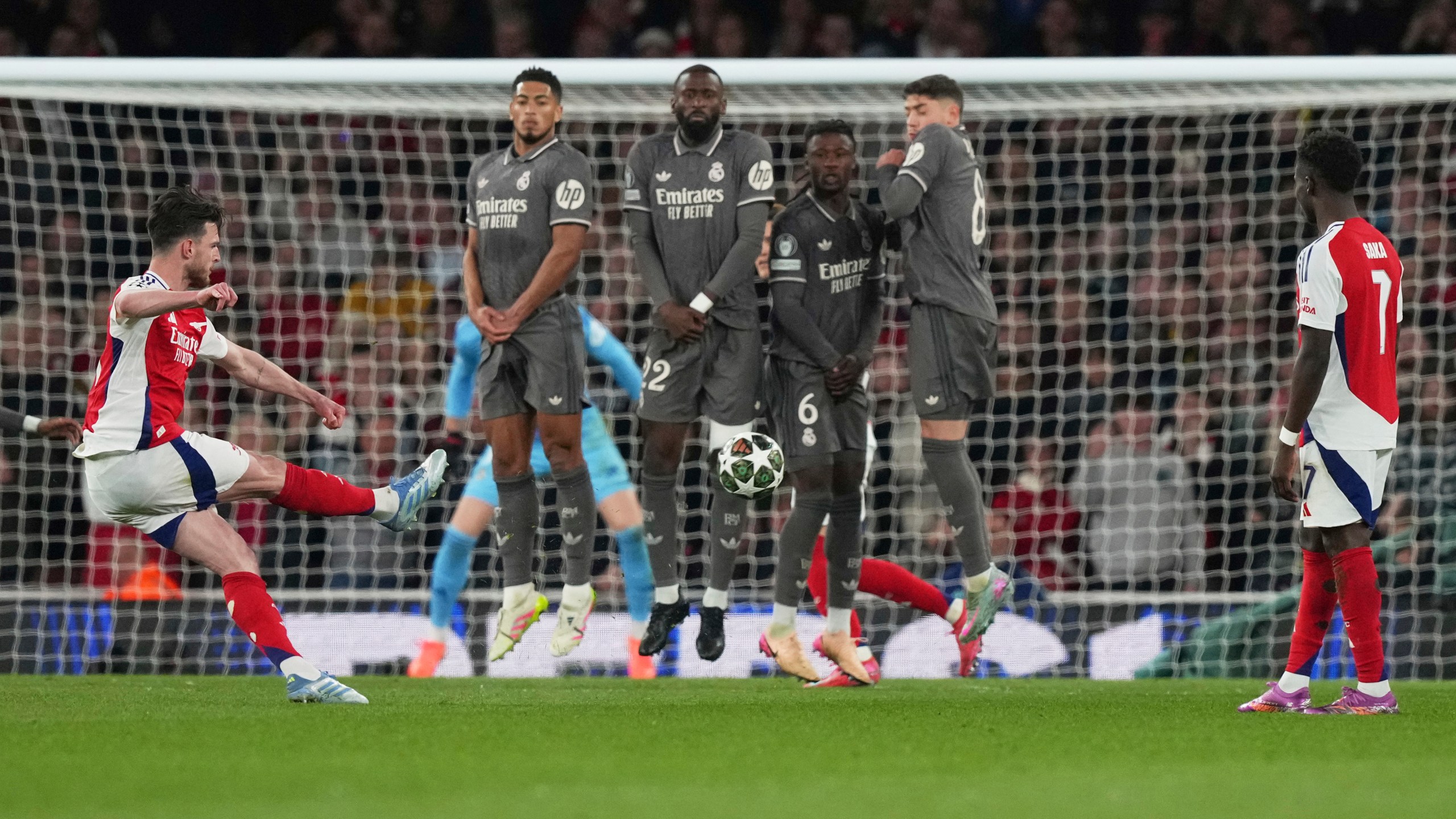 Arsenal's Declan Rice, left, scores his side's opening goal during the Champions League quarterfinal first leg soccer match between Arsenal and Real Madrid at the Emirates Stadium in London, Tuesday, April 8, 2025. (AP Photo/Frank Augstein)