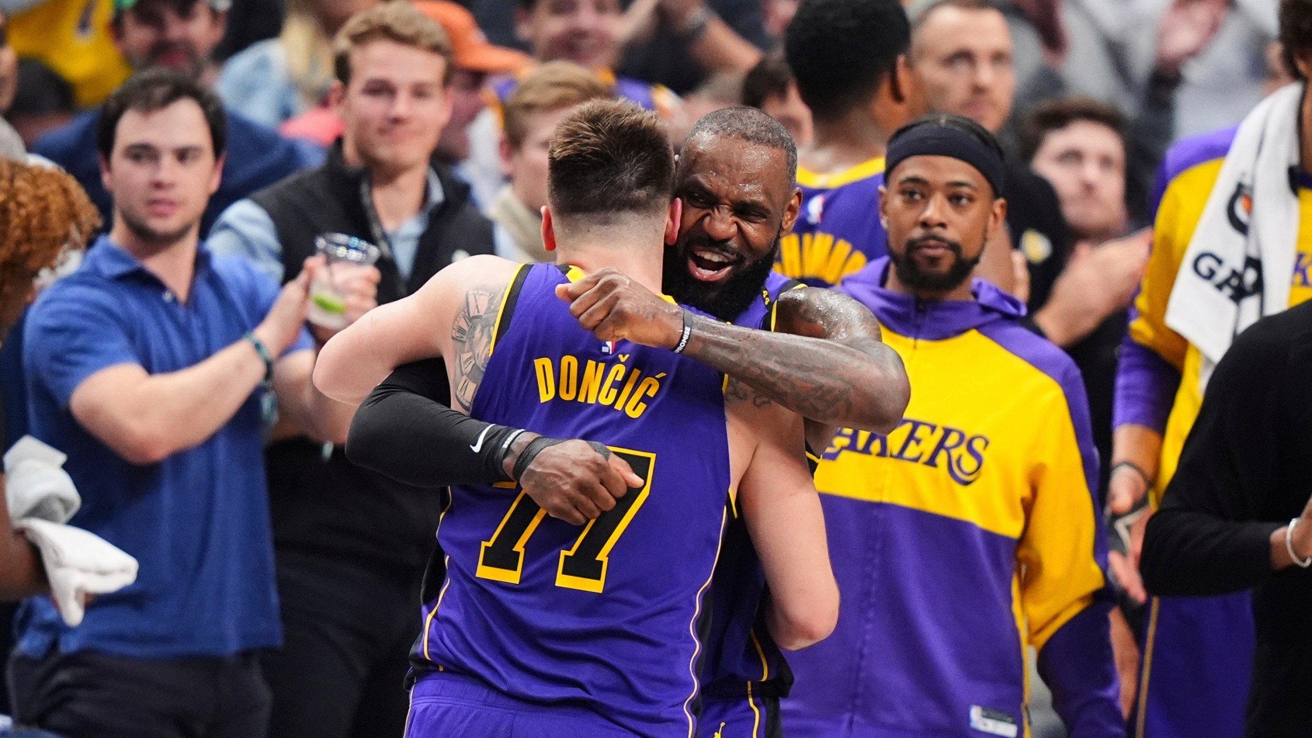 Los Angeles Lakers' Luka Doncic (77) and LeBron James, center, right, hug and celebrate late in the second half of an NBA basketball game against the Dallas Mavericks in Dallas, Wednesday, April 9, 2025. (AP Photo/LM Otero)