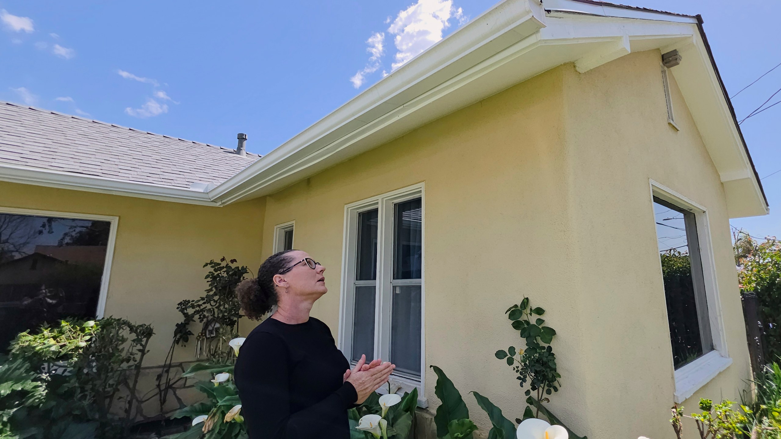 Eaton fire survivor Dr. Nicole Maccalla, a data scientist and a lead investigator, checks her roof's repairs made to her smoke damaged home in Altadena, Calif., on Friday, April 4, 2025. (AP Photo/Damian Dovarganes)