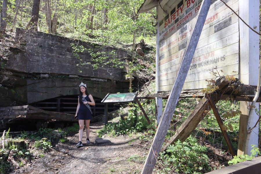 West Virginia Coal Festival teen beauty pageant winner Ava Johnson, 16, walks by a safety board at the former Kay Moor coal town and camp in the New River Gorge National Park and Preserve near Fayetteville, W.Va., Thursday, April 17, 2025, (AP Photo/Leah Willingham)