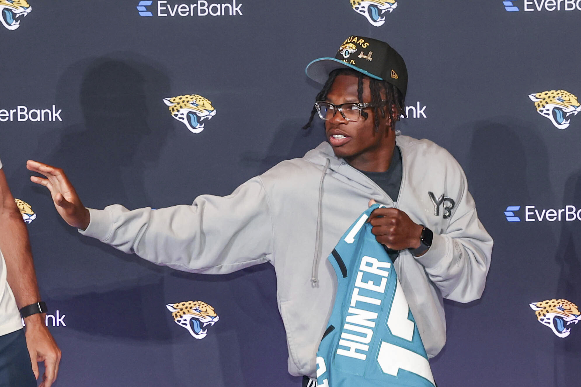 Two-way player Travis Hunter, the Jacksonville Jaguars first round draft pick, second overall, strikes a Heisman pose while holding a jersey during an NFL football press conference, Friday, April 25, 2025, in Jacksonville, Fla. (AP Photo/Gary McCullough)