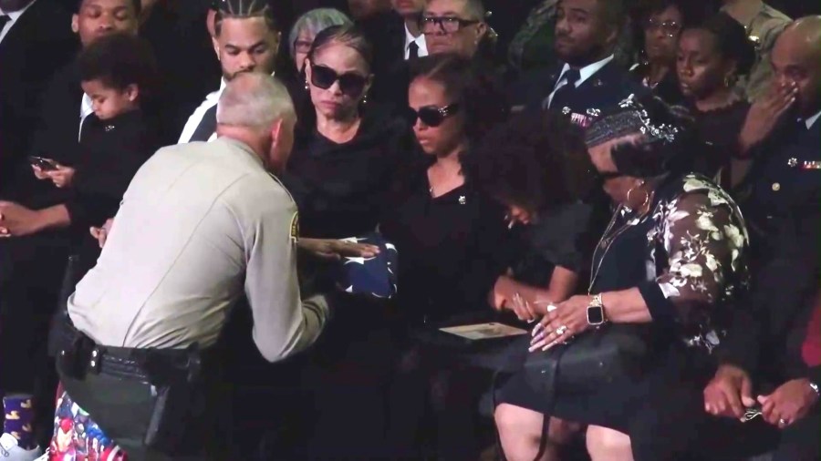 Hector Cuevas, Jr.'s wife, Mia Cuevas, is presented with an American flag at her husband's funeral service at the Ontario Convention Center on April 17, 2025. (KTLA)
