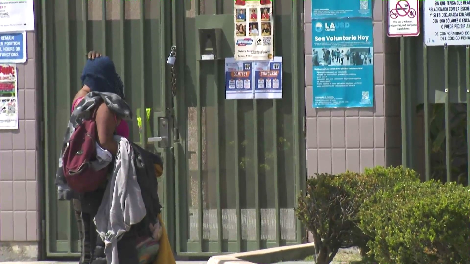 A transient woman is seen walking up to the gates of San Miguel Elementary School in South Gate in what parents and residents say is a growing problem affecting the school. (KTLA)